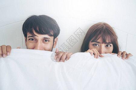 快乐的年轻夫妇在早上醒来后在家庭卧背景图片