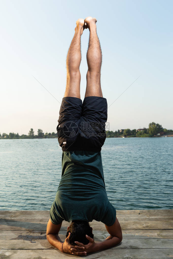 由天然背景的印度瑜伽大师在湖边摆姿势图片