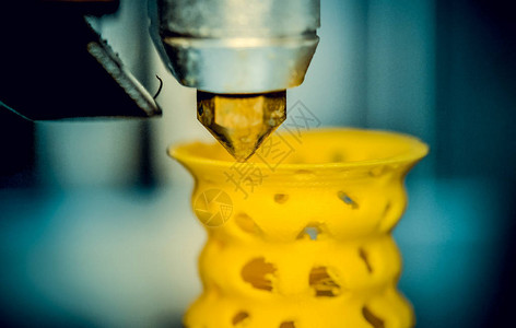 3D打印机从塑料特写中打印出来打印机在灰色平面上制作图片