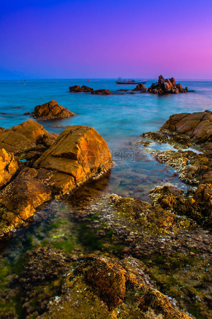 海浪在日落时撞击岩石图像中包含软焦点和蓝色图片