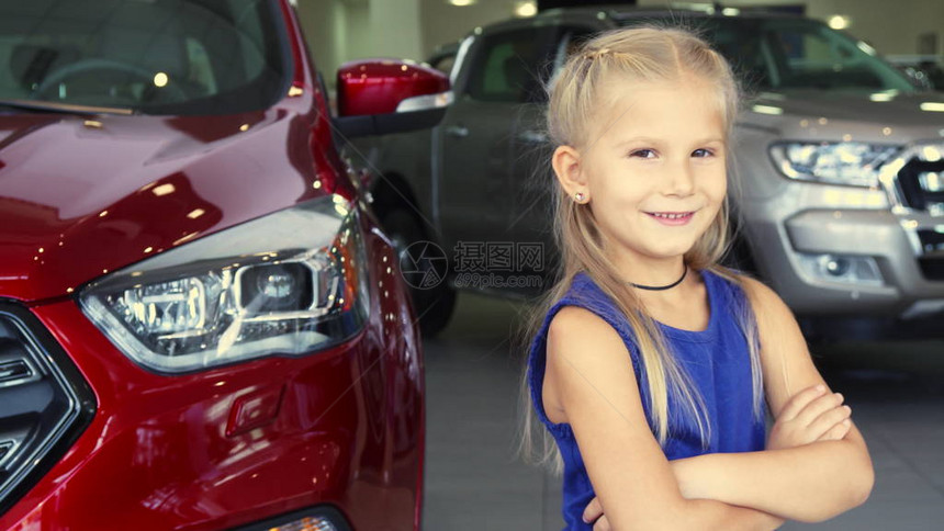 一个小女孩站在一辆车前她的双手交叠在胸前她看着镜头笑了图片
