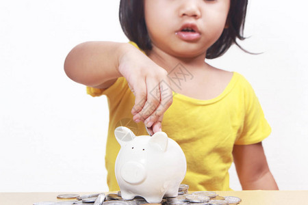 商业经济金融投资概念可爱的小亚洲女婴在她的小猪银行存图片