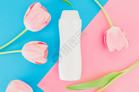 粉红和蓝色背景的香波瓶和郁金香花朵图片