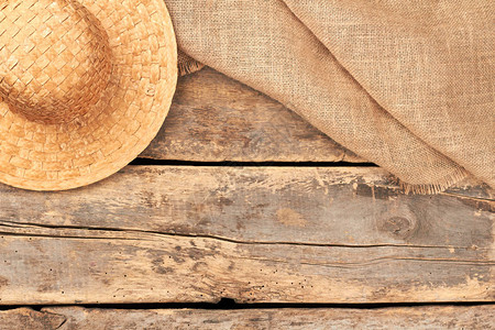粗麻布粗麻布解雇和草帽平躺背景与草帽和粗麻布织物在质朴的木地板背景图片