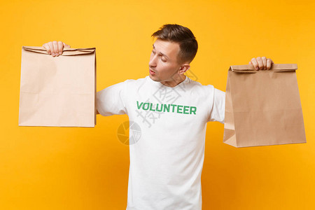 身穿白色T恤的男子肖像写着绿色志愿者拿着空白工艺纸袋图片