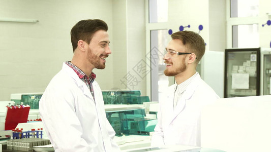 两个人站在实验室中间他们的工作有休息时间他们愉快地谈图片