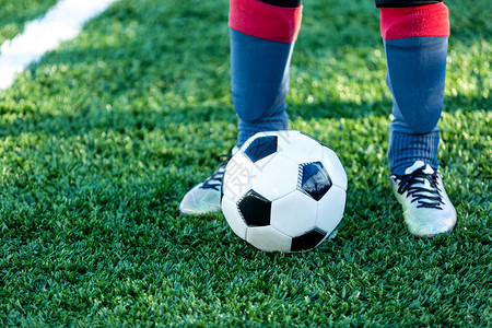 经典的足球在场的绿草和运动鞋的腿上足球比赛训练爱好概念图片