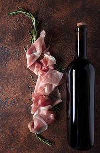 配有迷迭香和一瓶红酒的Prosciutto顶端视图片