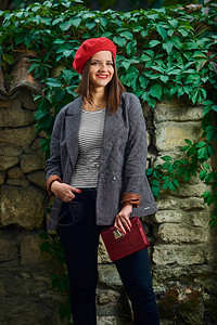 身穿红色贝雷帽的年轻女子拿着一只红色手提包图片