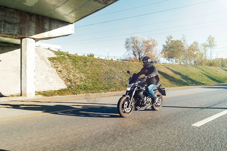 在美丽的秋天乘坐摩托车在空路上骑着摩托车离开城市远方图片