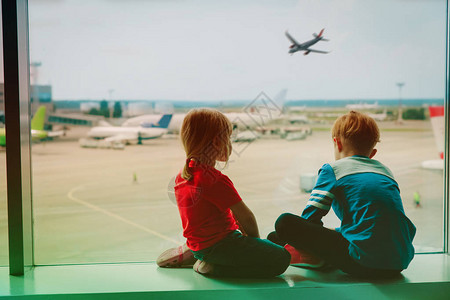 孩子们等着看机场的飞机家庭旅行概念图片