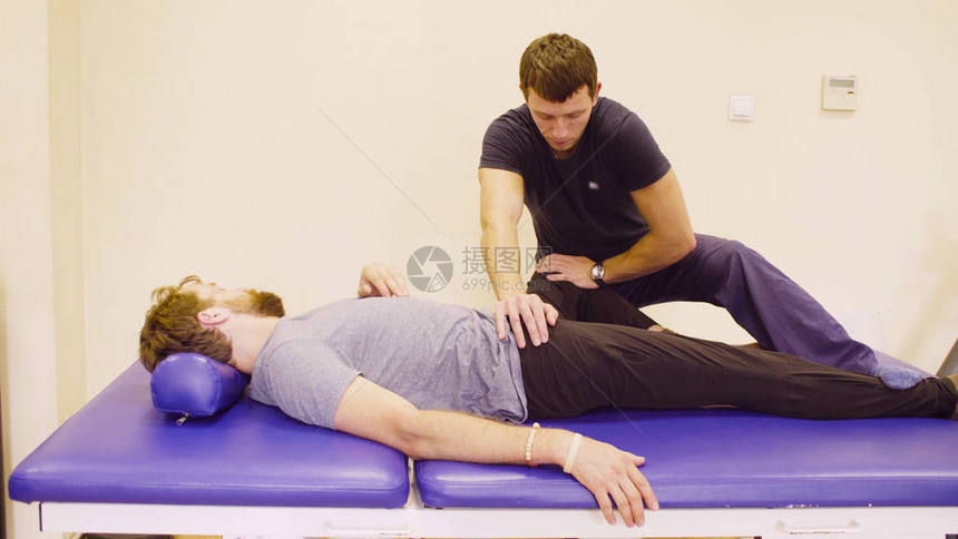 医生物理治疗师在康复诊所为年轻的残疾男子做伸展运动图片