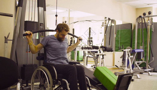 坐在轮椅上的年轻残疾男子在康复诊所进行体力锻图片