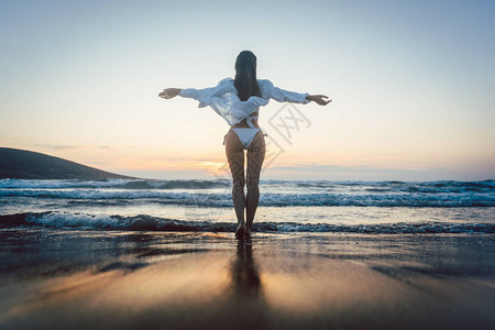 女人在日落的心情中享受她在海上度假的自由图片