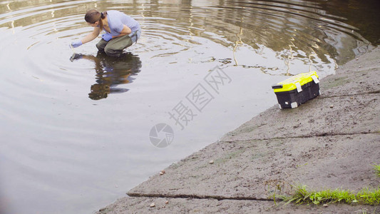 测量城市河流中pH值水分的女生态学家图片