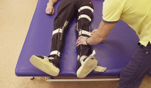 医生物理治疗师在康复中心将矫形器放在患者腿上图片