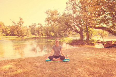 在河岸的美丽自然中静坐和做瑜伽锻炼时放松了一下身图片