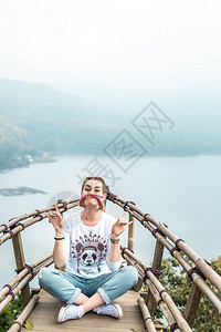 坐在山顶有热带湖背景的木桥上的年轻女子图片
