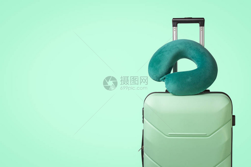 绿色背景上的塑料手提箱和旅行枕头旅行商务旅行探图片