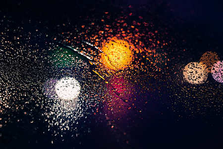 通过汽车挡风玻璃上的雨滴看到城市道路图片
