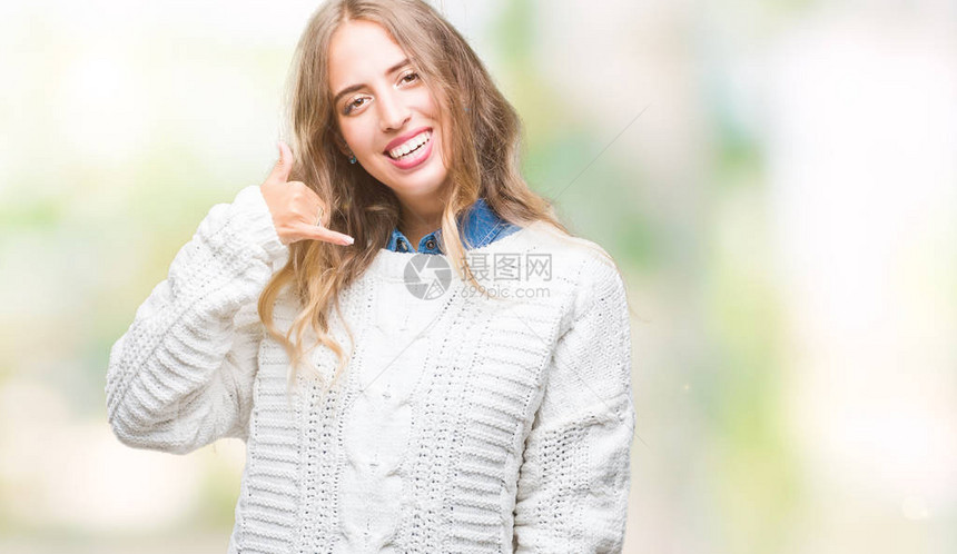 美丽的年轻金发女郎穿着冬季毛衣在孤立的背景下微笑着用手和指做电话手势图片