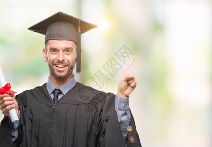 年轻英俊的毕业男子在孤立的背景下持有学位图片