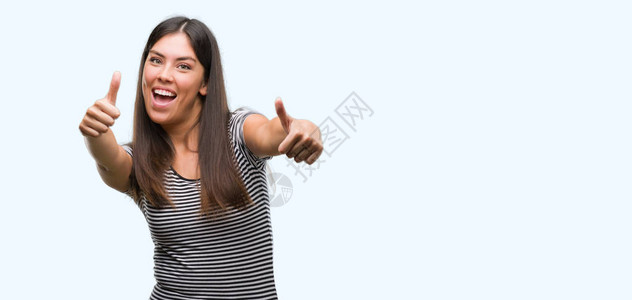 年轻美丽的西班牙女人赞同用手拇指笑起来图片