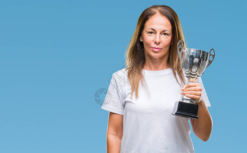 中年西班牙裔获奖者庆祝奖项的女在孤立的背景下举着奖杯背景图片