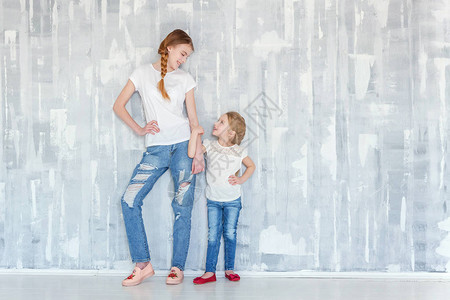 两个快乐的孩子站在灰色带纹理的墙壁背景和拥抱图片
