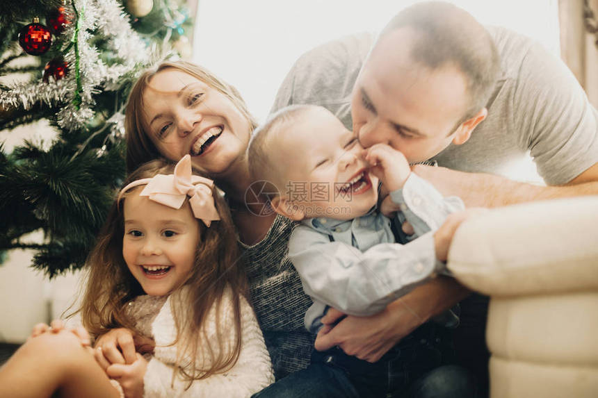 幸福的家庭拥抱彼此在圣诞树图片
