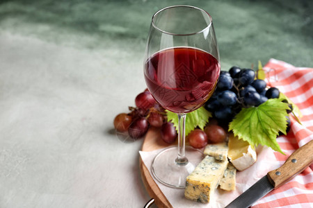 桌上有一杯葡萄酒新鲜葡萄和奶酪图片