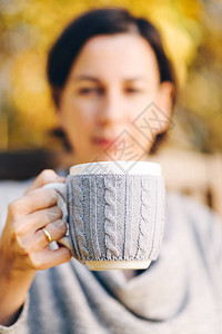 在秋天风景中握着一杯热茶咖啡的手图片