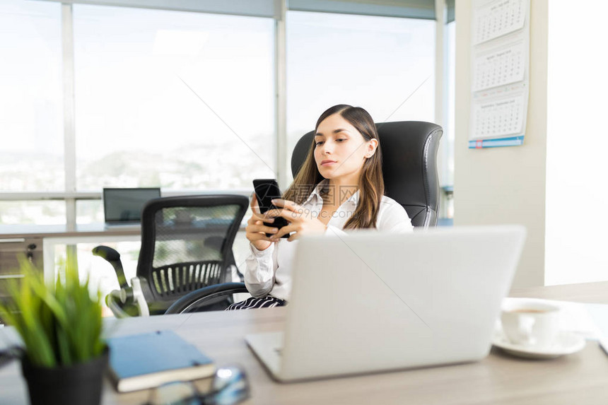 使用办公室智能手机在线应用软件的自信女咨询顾问图片