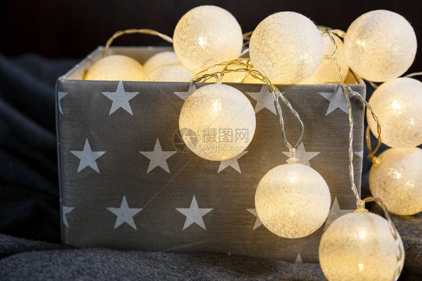 灰色篮子中的白色棉球灯花环与家中闪发光的星图片