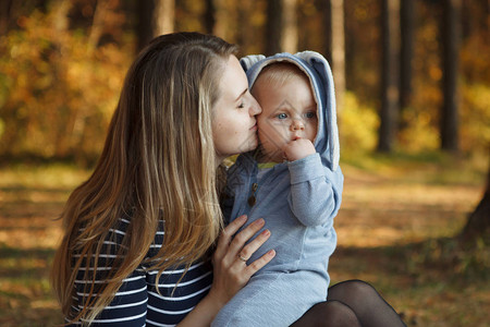 身穿蓝兔子西装的母亲和儿子坐在秋天森林背景图片