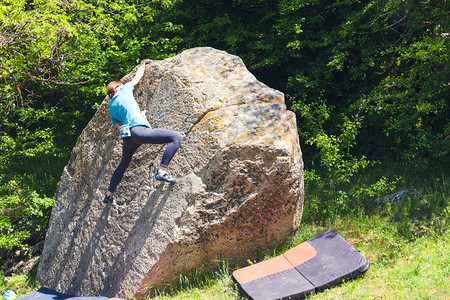 登山者本质上是抱石女孩爬上一块大石头在户外做运动的女人运动员图片
