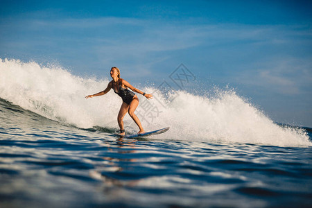 有冲浪板的年轻冲浪者妇女在波浪图片