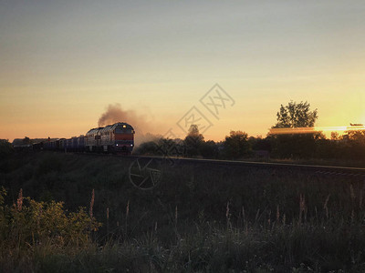日出时在铁路上行驶的低速货运列车破轨通勤列车火车站对晨晴天空图片