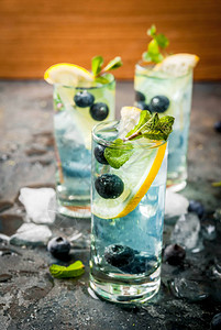 夏季茶点饮料蓝莓柠檬水或莫吉托鸡尾酒加柠檬新鲜蓝莓和薄荷深蓝色石头图片