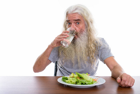 演播室拍摄的一张照片长胡子老人喝水杯配有沙拉盘子图片