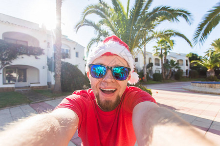 旅行节假日和圣诞节概念穿着圣诞老人帽子的帅哥在阳光明图片