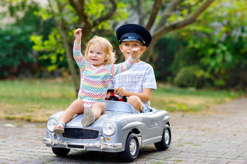 两个快乐的孩子在夏日花园里玩大旧玩具车图片