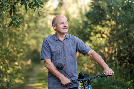 快乐的老人在阳光明媚的日子里在公园里骑自行车老年时的积极生活度图片