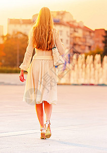 秋天春的时尚女人穿着城市街道和汽车女时尚女孩模特女式高脚跟落在户外的女风格的背面闪亮的喷泉阳光背景图片