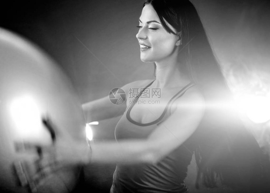 健身女孩瑜伽在带球的健身房里锻炼健身球的女人在光线运动室工作肖像的黑白照片在配置文件与镜头光晕和阴影图片