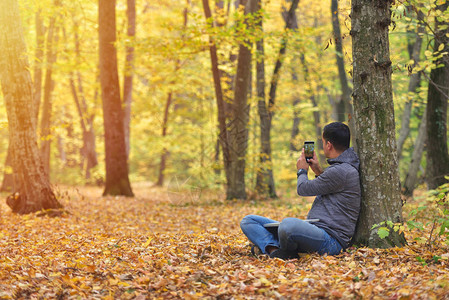 男人在森林秋色日落和温暖的阳光下拍摄图片