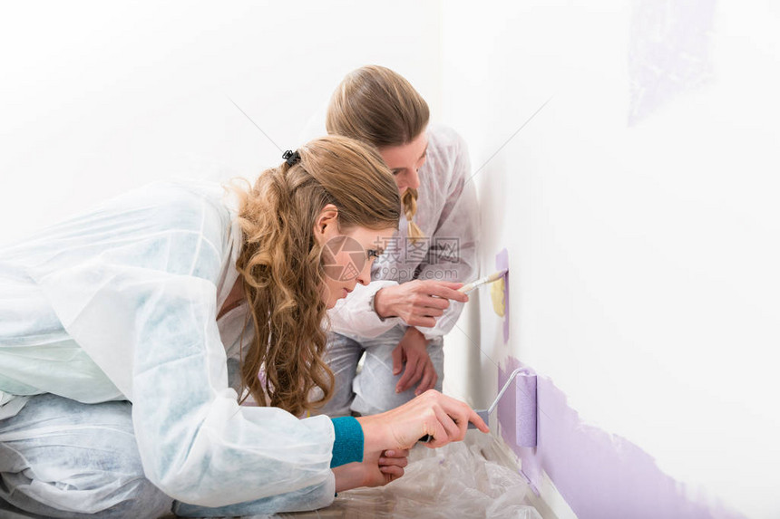 关闭两名女工在墙上用滚和油漆刷图片