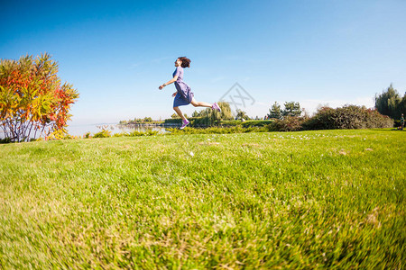 穿裙子的女孩跑过绿草地女人在公园里走动自然活动苗条的黑发美图片