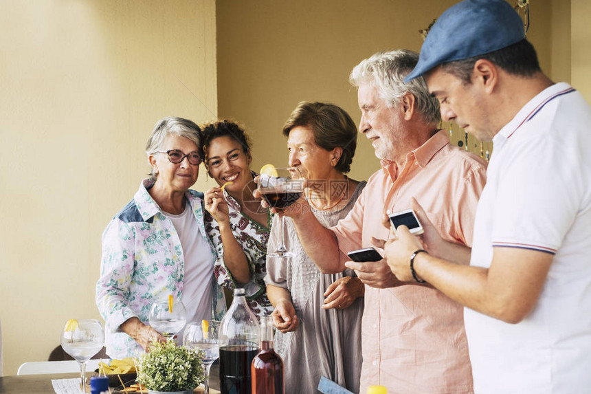 不同年龄和不同别的人在友谊中聚在一起吃晚餐或午餐男人玩手机和技术微笑图片
