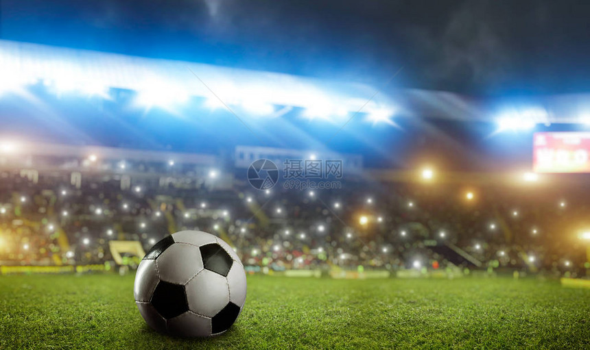体育场绿草上的足球特写镜头明亮的泛光灯和背景图片